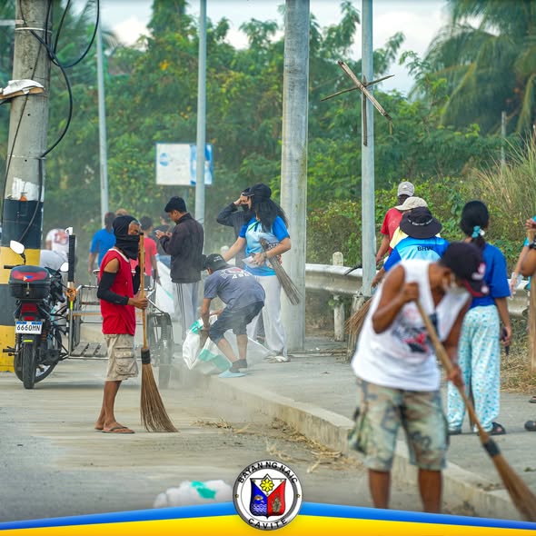 Mga boluntaryo na naglilinis gamit ang walis at supot sa gilid ng highway ng Barangay Muzon, Naic