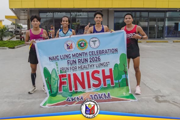 Apat na kalahok ng Naic Lung Month Fun Run 2026 na may hawak na FINISH banner sa harap ng gusali
