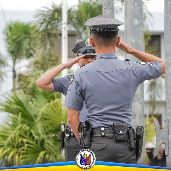 Dalawang uniporme na tauhan na nagsasaludo habang nagfa-flag raising sa Naic Municipal Hall