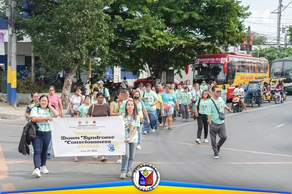 Mga kalahok na naglalakad sa kalsada habang hawak ang banner ng Down Syndrome Consciousness Month sa Naic