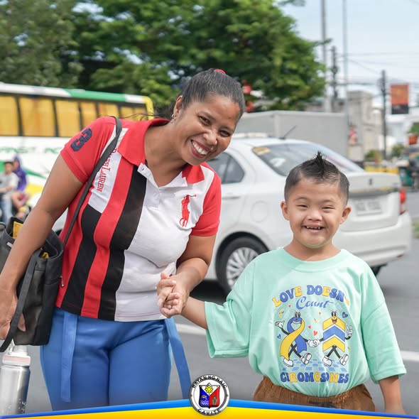 Ngiti ng isang ina at anak habang naglalakad sa kalsada ng Jollibee Highway, Naic, sa pagdiriwang ng Down Syndrome Awareness