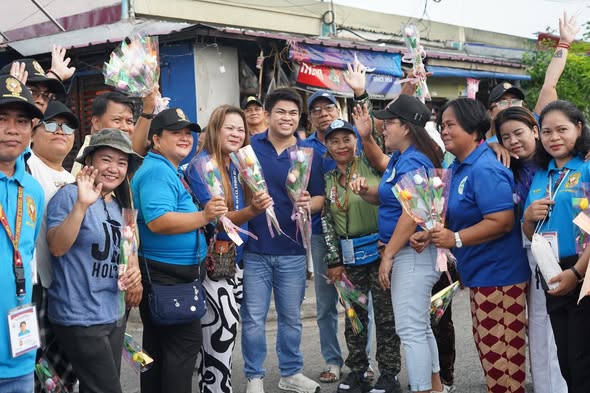 Mga tao na may hawak na bulaklak at kumakaway sa kalsada habang namamahagi ng bulaklak sa Araw ng mga Puso
