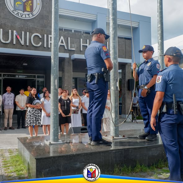Mga pulis na nagtataas ng watawat sa harap ng Naic Municipal Hall sa unang Flag Raising Ceremony ng Hunyo