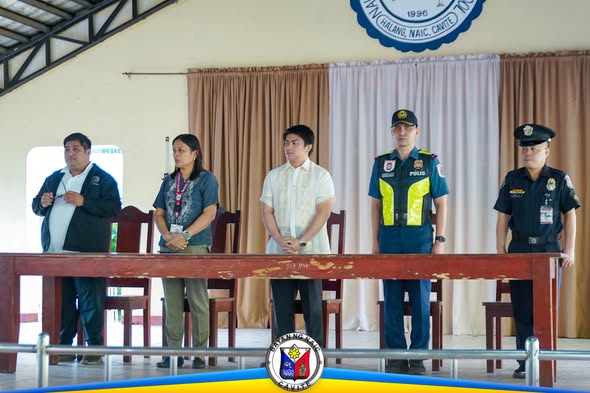 Mga opisyal at pulis na nakatayo sa likod ng mesa sa flag ceremony ng Naic INHS
