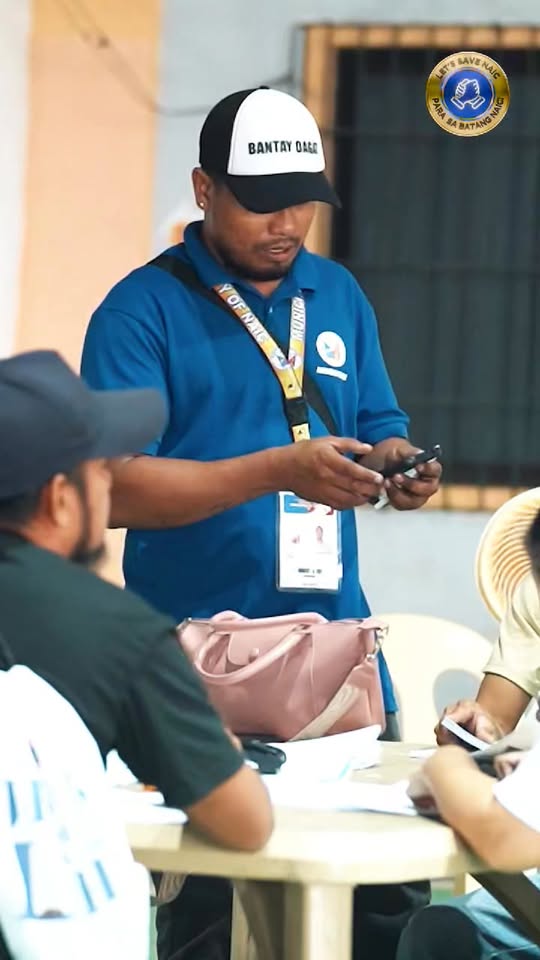 Staff na nagre-register ng mangingisda gamit ang cellphone sa mesa sa covered court ng Bagong Karsada