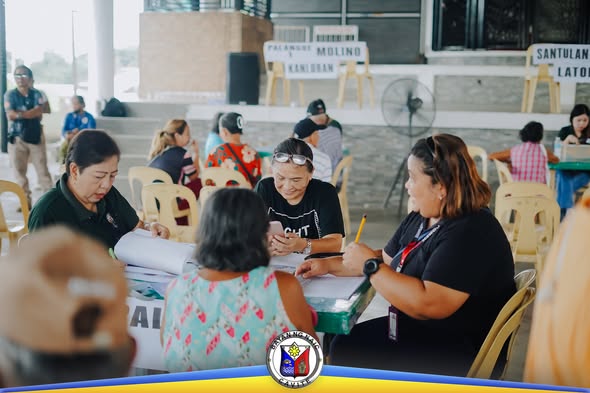 Mga kawani ng pamahalaan habang nagbeberipika ng dokumento sa pamamahagi ng social pension sa Naic Town Plaza