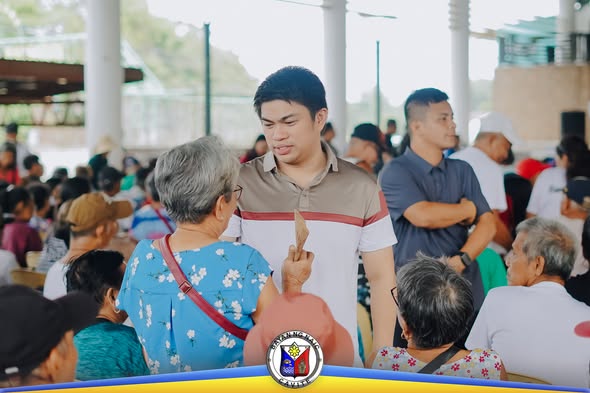 Mga senior citizen na nakapila at nakaupo sa Naic Town Plaza habang may pamamahagi ng social pension