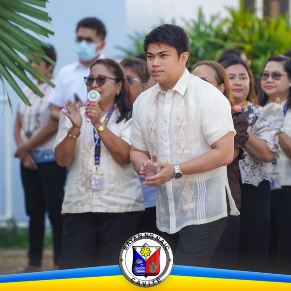 Litrato: Lalaking naka-barong habang nakatayo sa flag raising ceremony sa Naic Municipal Hall, kasama ang mga kawani
