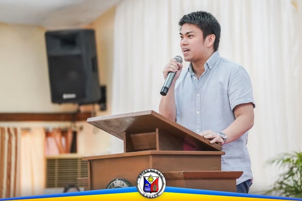Lalaking nagsasalita sa mikropono sa podium habang nagseseminar sa Daluyan Community Center, Naic