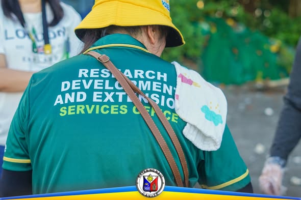Tao na naka-green na damit na may print na Research Development and Extension Services Office habang nagko-coastal clean-up