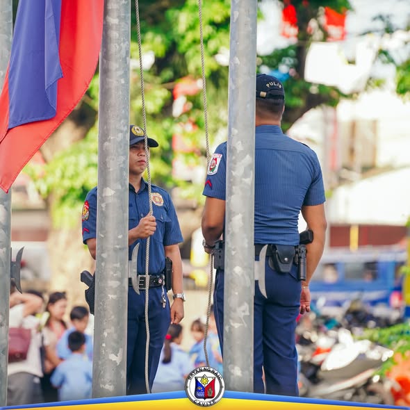 Mga pulis na nakatayo sa tabi ng flagpole habang isinasagawa ang flag raising ceremony sa Naic Municipal Hall