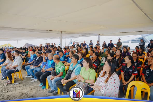 Mga taong nakaupo sa ilalim ng tent habang nagaganap ang groundbreaking ng Convention Center sa Naic