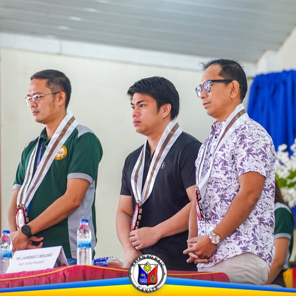 Tatlong lalaking nakatayo sa programa ng Entrepreneurship Day sa Naic, may suot na medalya