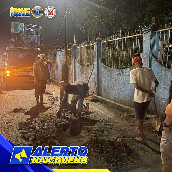 Mga tauhan naglilinis ng kalsada at kanal sa gabi malapit sa pader sa San Roque Crossing, Naic