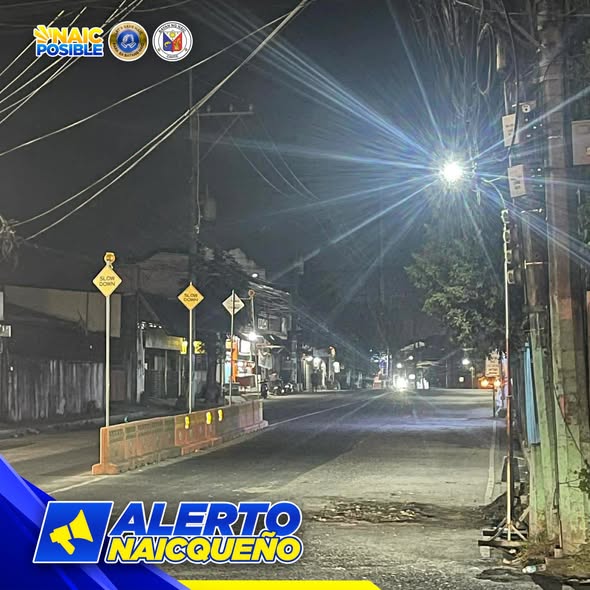Kalsada sa gabi sa San Roque Crossing na may mga karatulang 'Slow Down' at harang na kongkreto