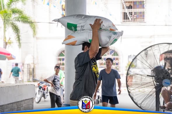 Lalaking nagbubuhat ng sako ng binhi sa covered area ng Naic Town Plaza habang namamahagi ng RCEF seeds