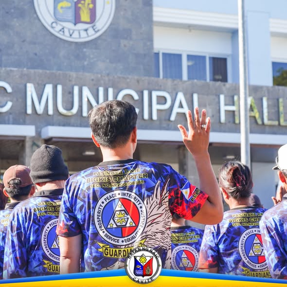 Mga miyembro ng Bigkis Chapter na nakatayo sa harap ng Naic Municipal Hall habang nagtataas ng kamay sa flag raising