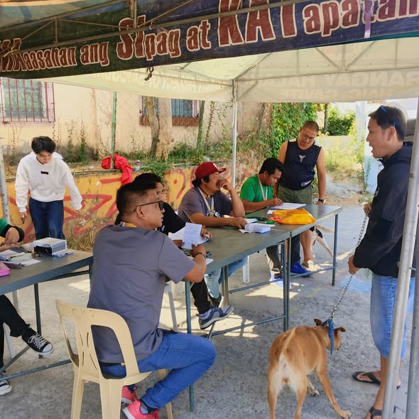 Mga kawani at tagapag-alaga ng aso sa anti-rabies vaccination sa ilalim ng tent sa Barangay Halang