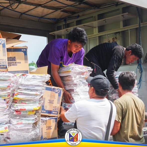Mga kalalakihan na nag-aayos ng mga notebook at school supplies sa covered area para sa pamamahagi sa mga paaralan
