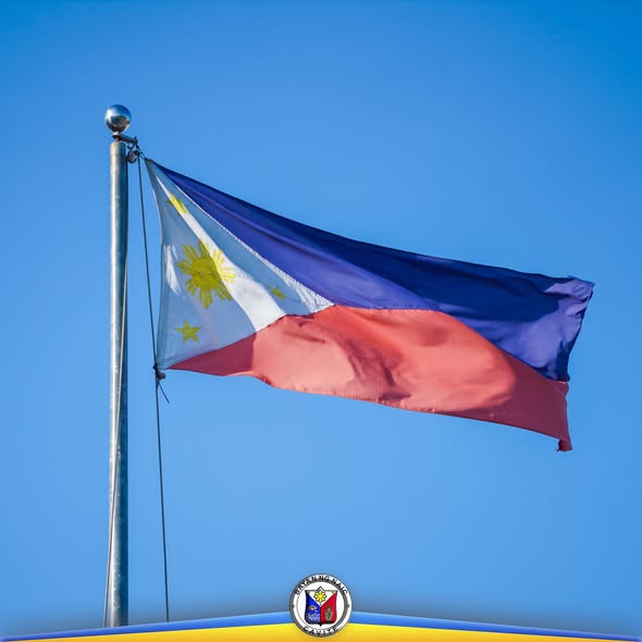 Watawat ng Pilipinas na kumakaway sa malinaw na kalangitan, may selyo ng Bayan ng Naic