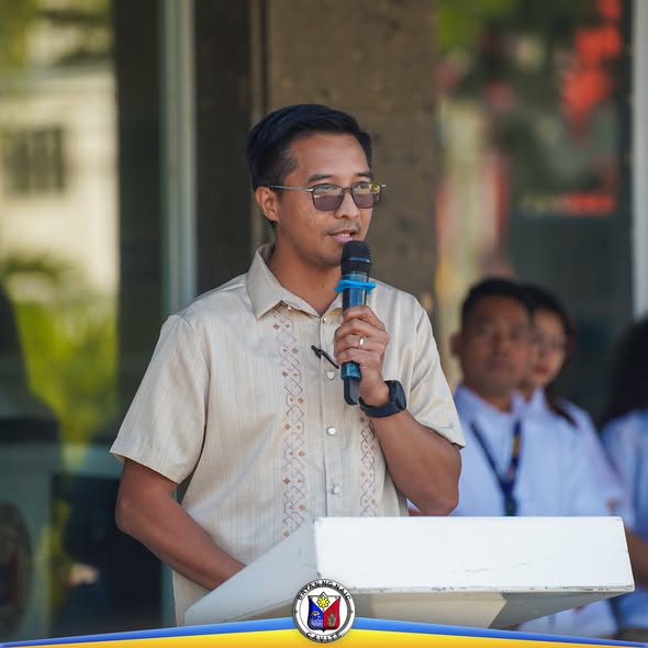 Lalaking nagsasalita sa mikropono sa podium habang nasa flag raising ceremony sa Naic Municipal Hall