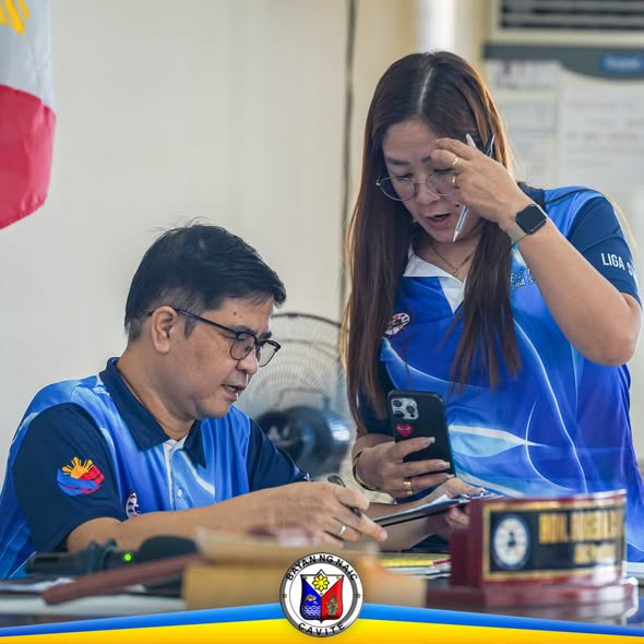 Dalawang opisyal sa Liga ng mga Barangay meeting sa ABC Hall, nagsusulat at nagbabasa ng telepono