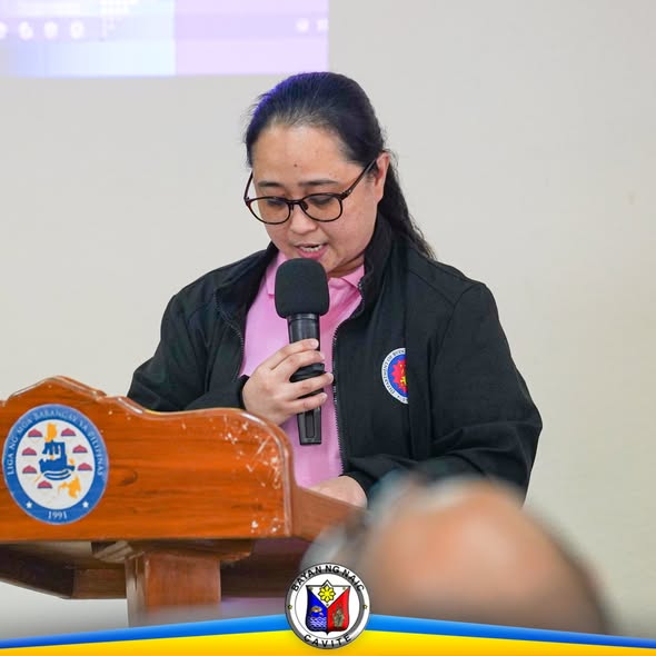 Babaeng nagsasalita sa mikropono sa podium ng Liga ng mga Barangay sa pulong buwanan