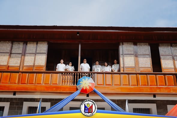 Mga opisyal na nakatayo sa balkonahe ng Casa Hacienda de Naic habang binubuksan muli ang gusali