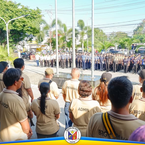 Flag raising ceremony sa Naic: mga kawani at uniformed personnel na nakahanay sa plasa habang may seremonya