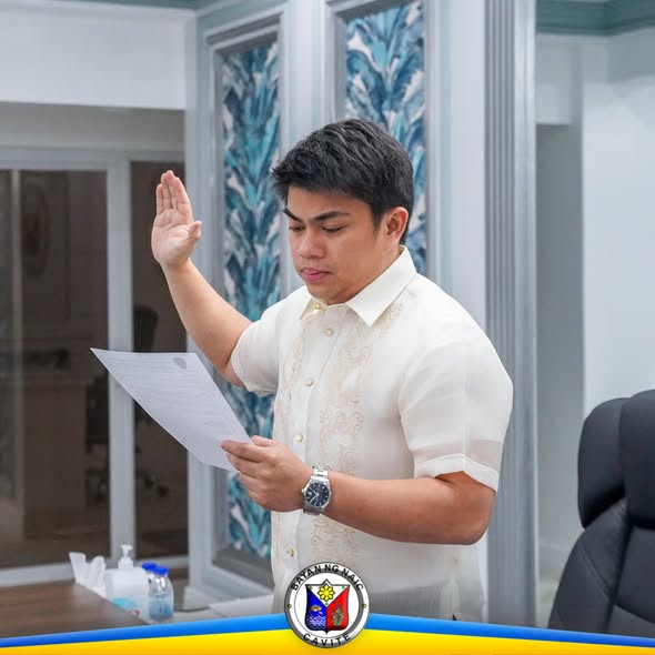 Lalaking nanunumpa habang nakataas ang kanang kamay at hawak ang papel sa loob ng opisina