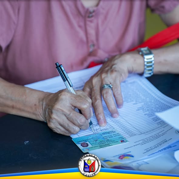 Matandang nagsusulat sa form habang may nakalatag na ID card sa mesa sa Localized Social Pension