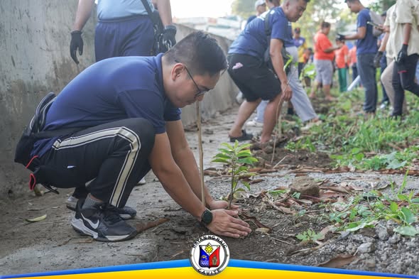 Tree planting: lalaking nagtatanim ng punla sa gilid ng Convento Bridge, kasama ang mga kalahok sa Naic Arbor Day