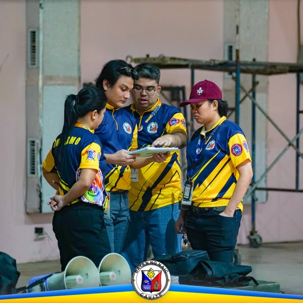 Mga tauhan ng MDRRMO na nagtutulungan at tinitingnan ang papel sa loob ng hall habang may earthquake drill