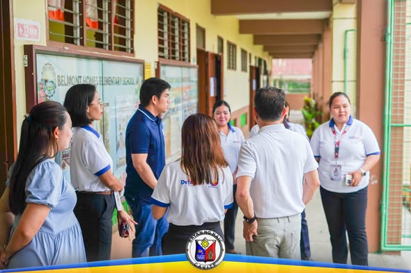 Mga kawani ng paaralan at opisyal na nag-uusap sa pasilyo ng Belmont Homes Elementary School