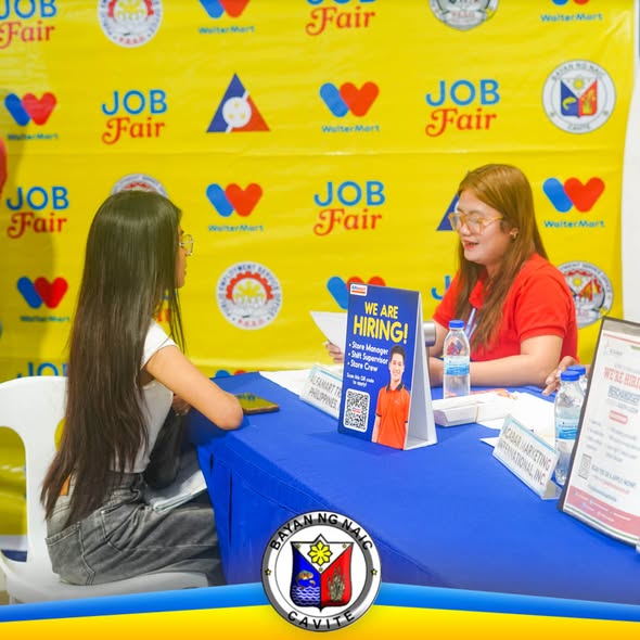 Job fair sa Waltermart Naic: recruiter na nakikipag-usap sa aplikante sa booth na may "We Are Hiring" sign