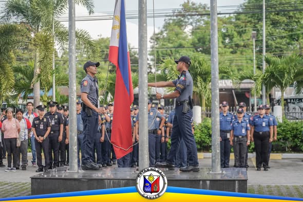 Flag raising ceremony sa Naic Municipal Hall, mga pulis at kawani habang itinataas ang watawat
