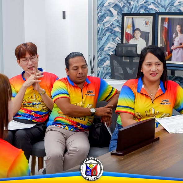 Mga miyembro ng LGBTQIA+ Pilipinas One Naic na nakaupo at nakikinig sa oath-taking sa loob ng opisina