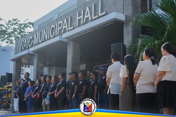 Mga kawani ng Naic Municipal Hall na nakatayo nang maayos sa harap ng gusali habang may flag raising ceremony