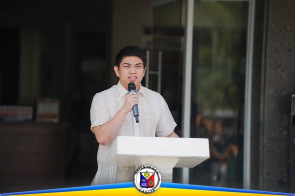 Lalaking nagsasalita gamit ang mikropono sa podium sa Flag Raising Ceremony, Naic Municipal Hall