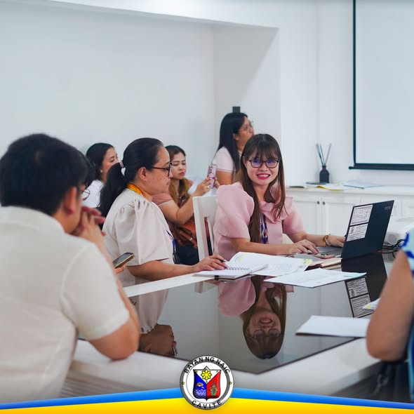 Pulong ng Local School Board sa Naic Municipal Hall, may mga kalahok na nakaupo sa mesa at may laptop