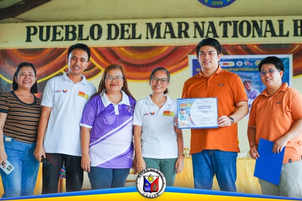 Mga kawani at estudyante habang hawak ang sertipiko sa entablado ng Pueblo del Mar National High School