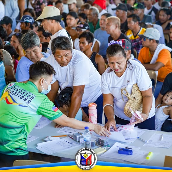 Mga residente na tumatanggap ng tulong sa relief operations sa mesa habang may staff ng Disaster Operations