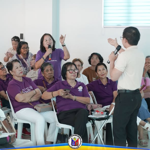 Mga senior citizen na nakikinig habang may nagsasalita sa mikropono sa Mid-Year Evaluation sa Naic