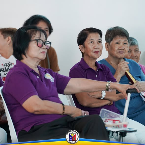 Mga nakatatandang kalahok na nakaupo at nanonood sa Mid-Year Evaluation ng Senior Citizens Program sa Naic