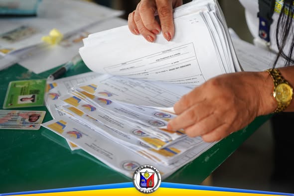 Mga kamay na nag-aayos ng mga papeles at tarheta ng tulong sa Naic Town Plaza