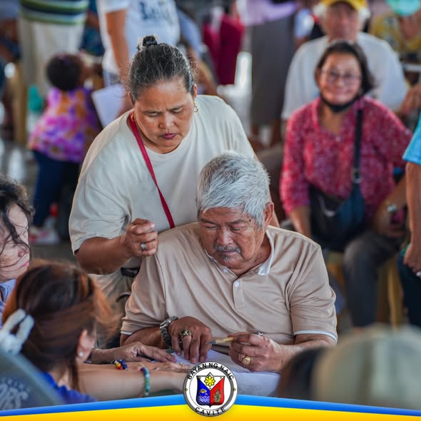 Matandang lalaki na tinutulungan ng babaeng staff habang nagpapasa ng papeles sa pamamahagi ng senior citizen incentives