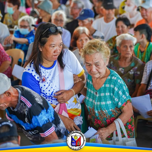Mga senior citizen na tumatanggap ng incentives habang inaalalayan ng kawani sa Naic Town Plaza