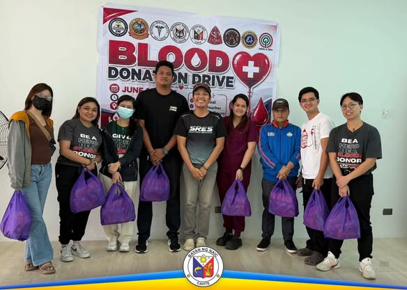 Grupo ng mga boluntaryo at kawani na may hawak na supot sa Blood Donation Drive sa Triple 8, Sabang, Naic