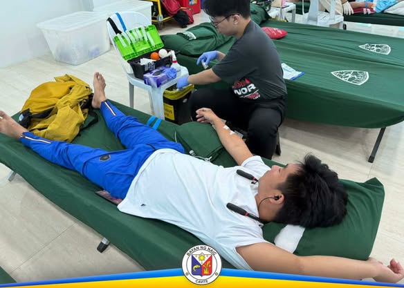 Donor na nakahiga habang inaasikaso ng staff ang pagkuha ng dugo sa Blood Donation Drive sa Sabang, Naic