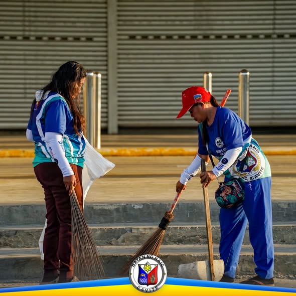 Mga kawani habang naglilinis gamit ang walis sa plaza sa Brgy. Sabang, Naic, Cavite